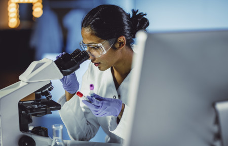 female medical researcher at microscope