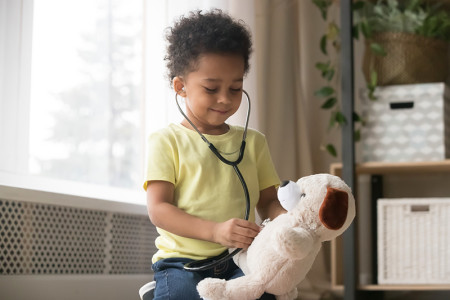 Toddler listening to a stuffed animal's heart with a stethoscope.