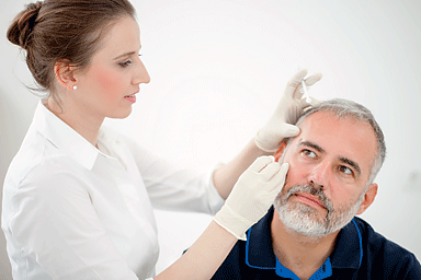 Dermatologist performing surgical removal of a cancerous spot on patient's face